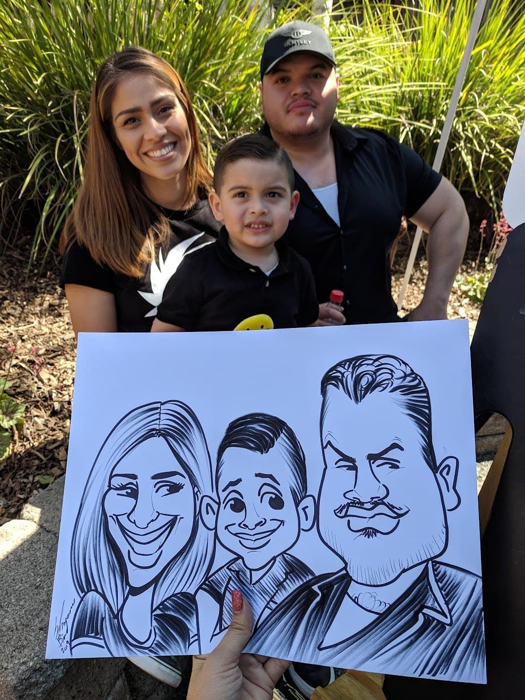 Family holding a three-person caricature