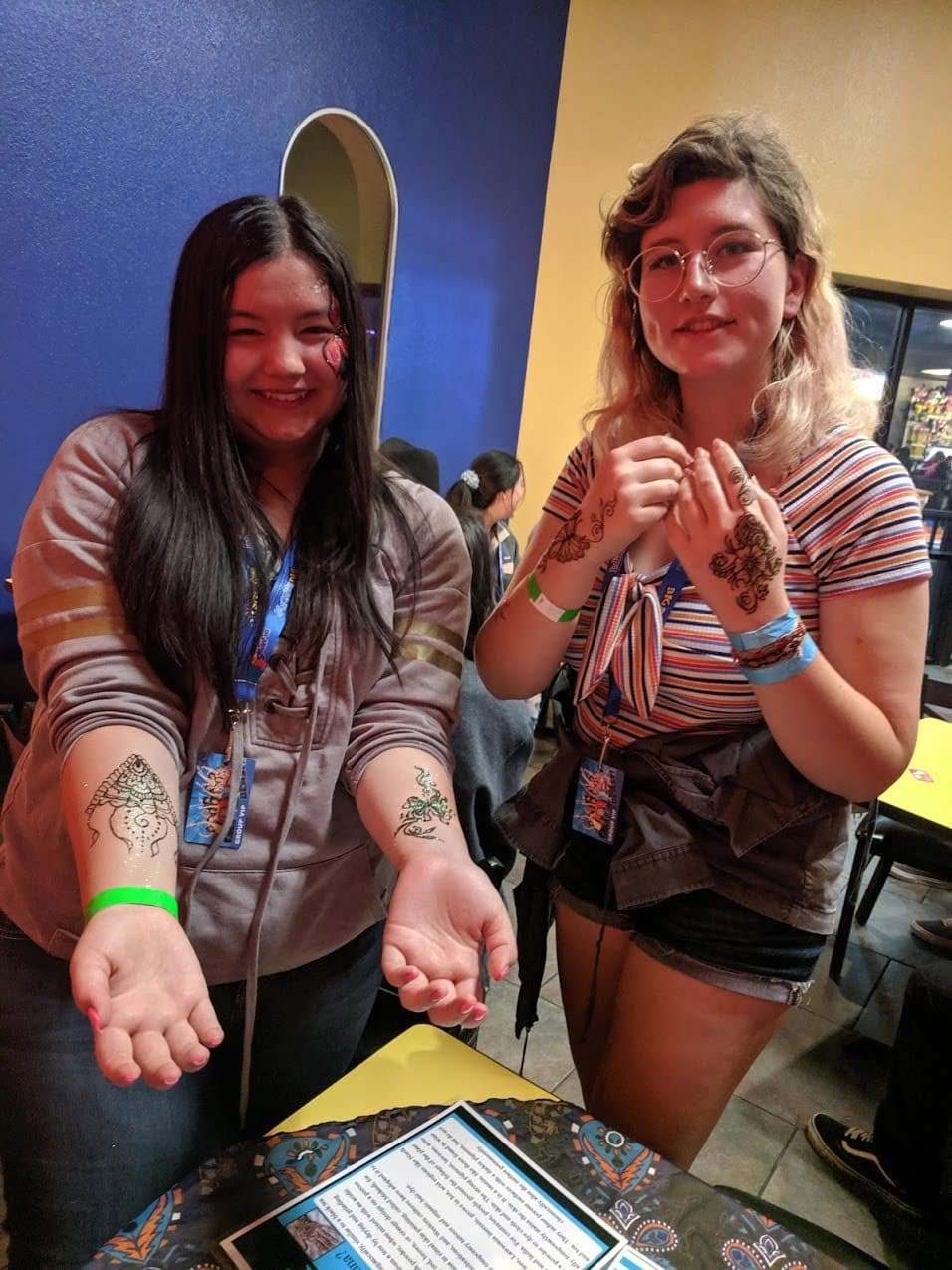 Two guests showing henna designs on wrists and hands