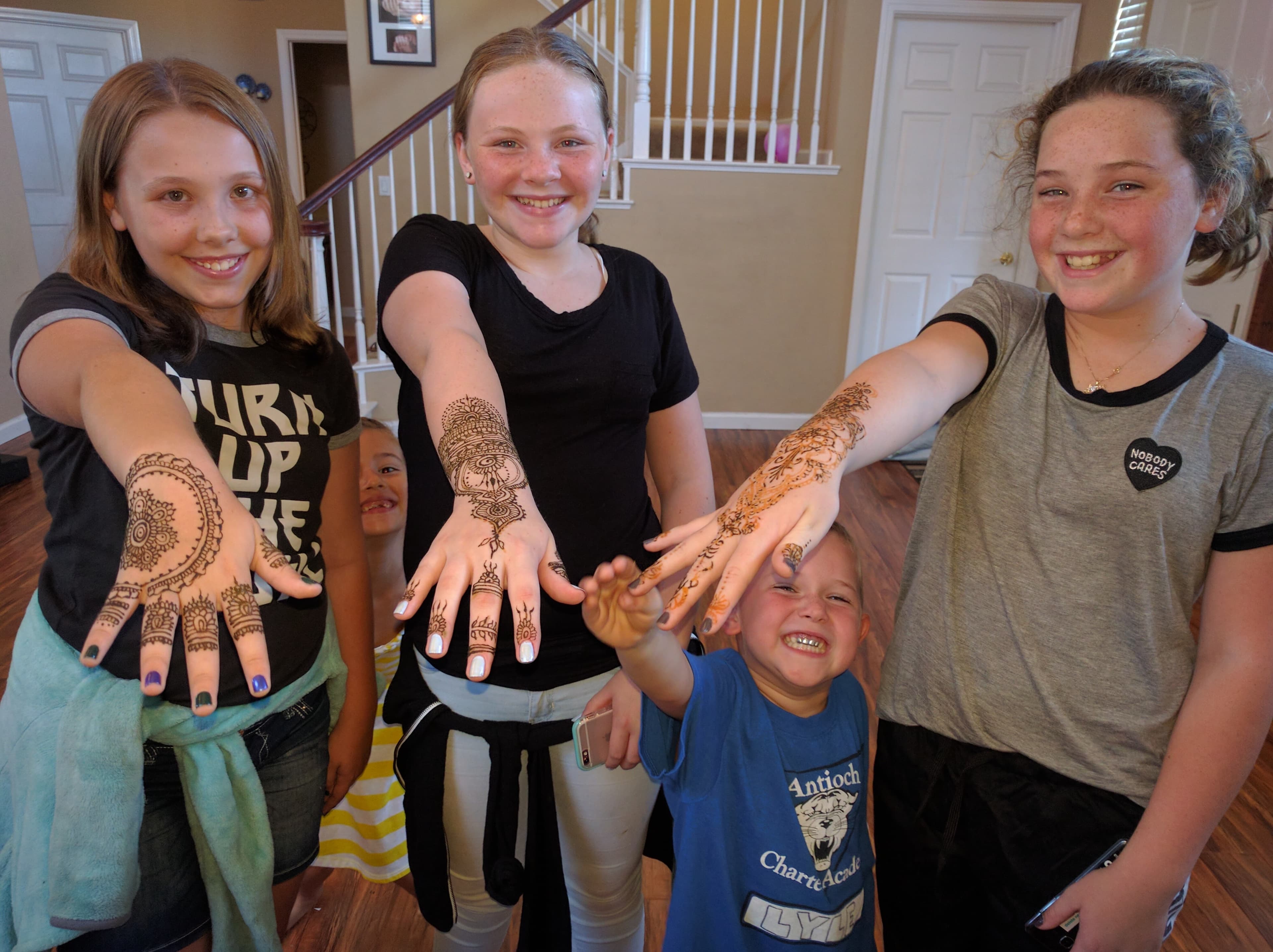 Kids at a party showing intricate henna on their hands